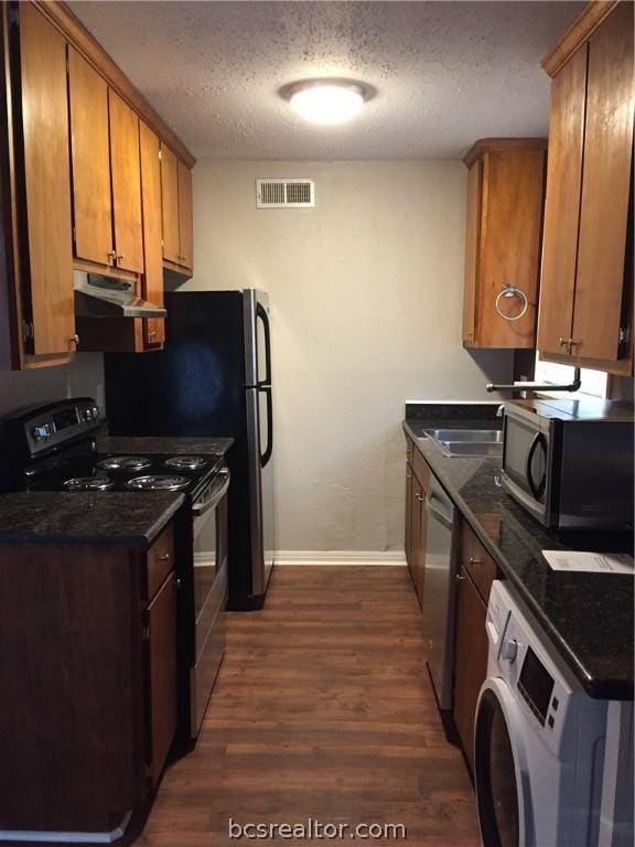 kitchen featuring washer / dryer, appliances with stainless steel finishes, a textured ceiling, and dark wood-type flooring