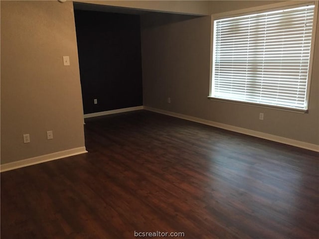 unfurnished room with dark wood-type flooring