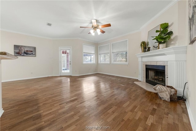 unfurnished living room with baseboards, ornamental molding, a tiled fireplace, and wood finished floors