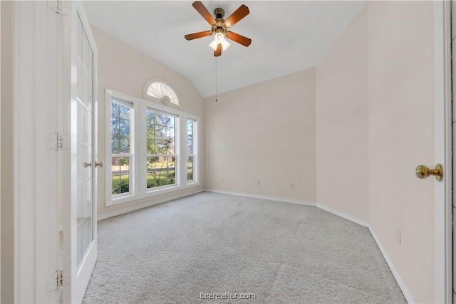 empty room featuring carpet floors, lofted ceiling, ceiling fan, and baseboards