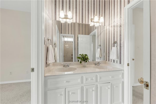 full bathroom with double vanity, a sink, baseboards, and wallpapered walls