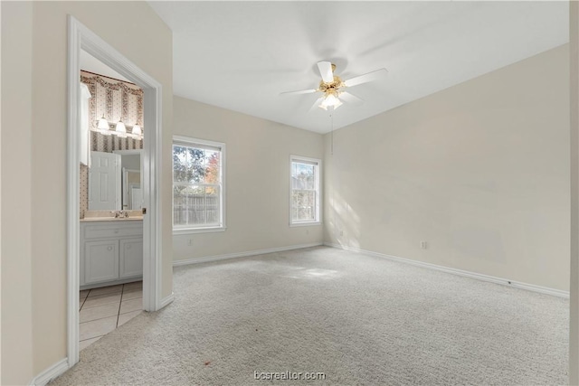 spare room with a ceiling fan, light carpet, and baseboards