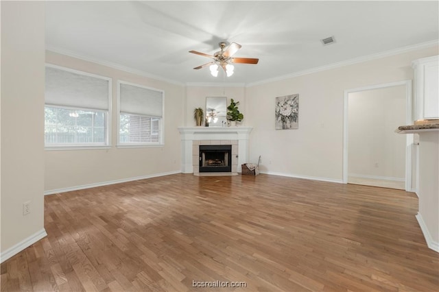 unfurnished living room with light wood-style flooring, visible vents, a ceiling fan, ornamental molding, and a tiled fireplace