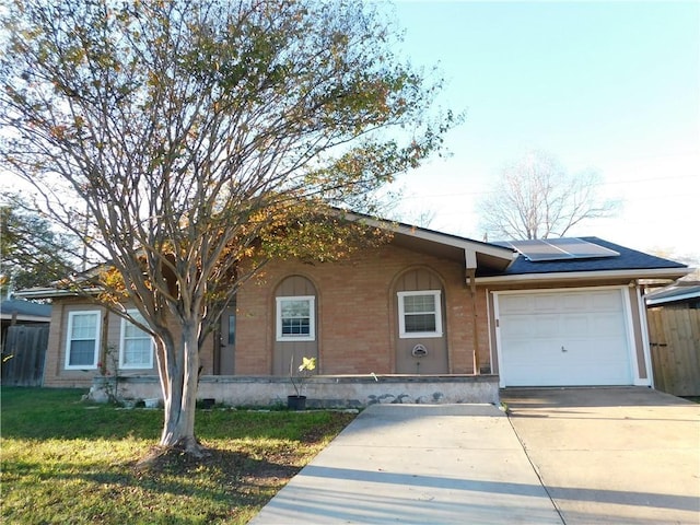 ranch-style house with solar panels, a garage, and a front lawn