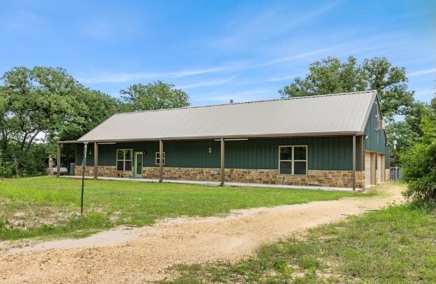 3205 County Road 308, Caldwell, TX 77836 - single story home featuring stone siding, a front yard, metal roof, and central air condition unit
