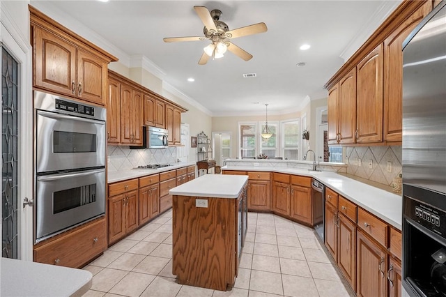 kitchen with light countertops, appliances with stainless steel finishes, tasteful backsplash, and brown cabinets