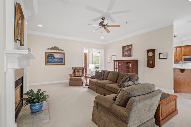 living room with ornamental molding, light carpet, a fireplace, baseboards, and ceiling fan