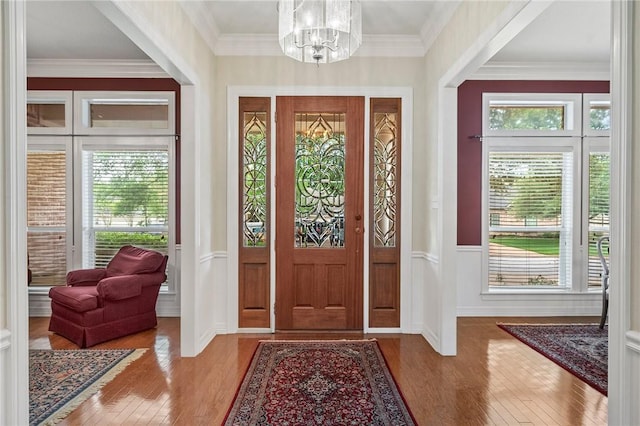 entryway featuring crown molding, wainscoting, hardwood / wood-style flooring, and a chandelier