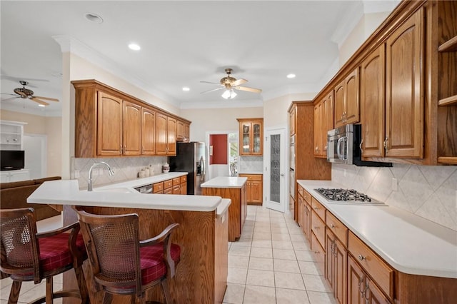 kitchen featuring a ceiling fan, appliances with stainless steel finishes, ornamental molding, and tasteful backsplash