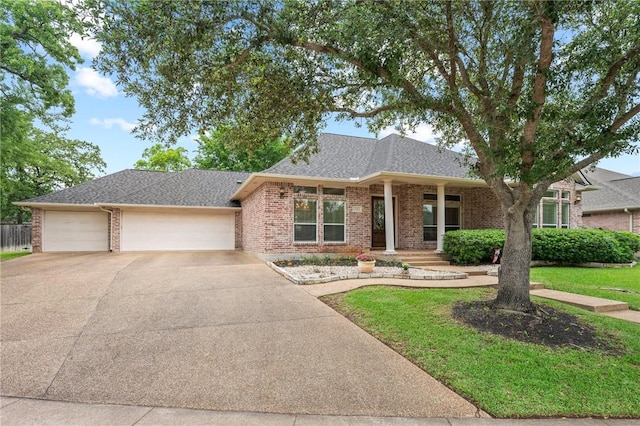 single story home featuring roof with shingles, a garage, brick siding, a front lawn, and concrete driveway