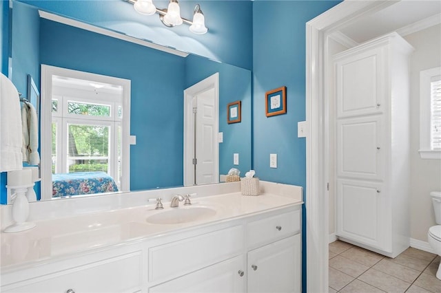 ensuite bathroom featuring vanity, toilet, baseboards, tile patterned floors, and ensuite bath