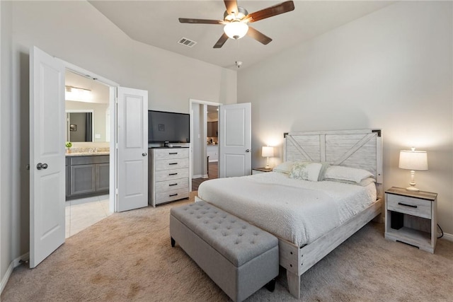 bedroom featuring light colored carpet, visible vents, a ceiling fan, ensuite bath, and baseboards