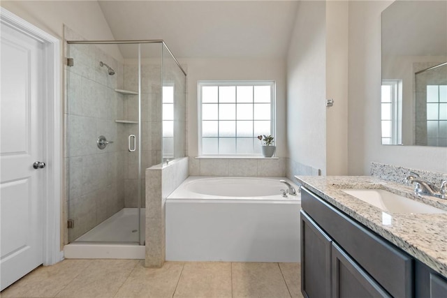 bathroom featuring lofted ceiling, vanity, a bath, tile patterned floors, and a stall shower