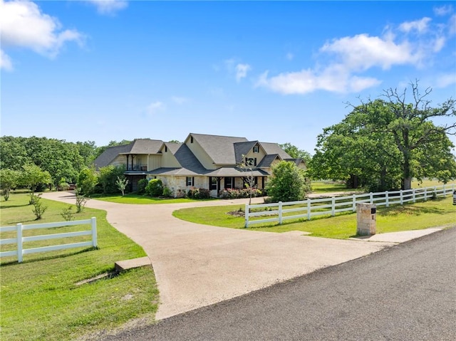view of front of property with fence, stone siding, a front lawn, and curved driveway