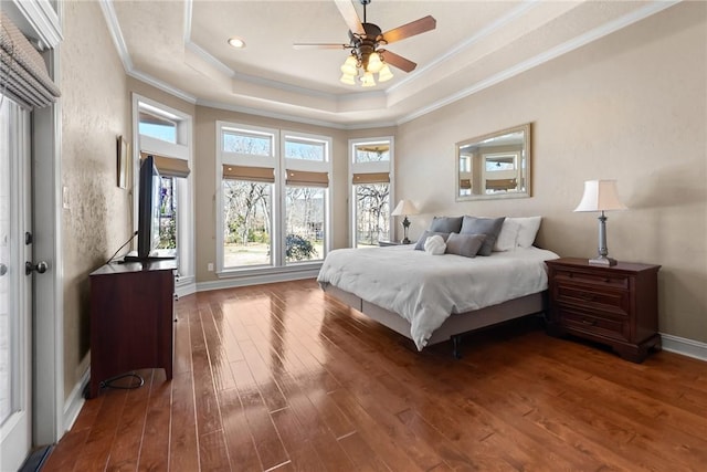 bedroom featuring baseboards, hardwood / wood-style floors, a tray ceiling, and ornamental molding