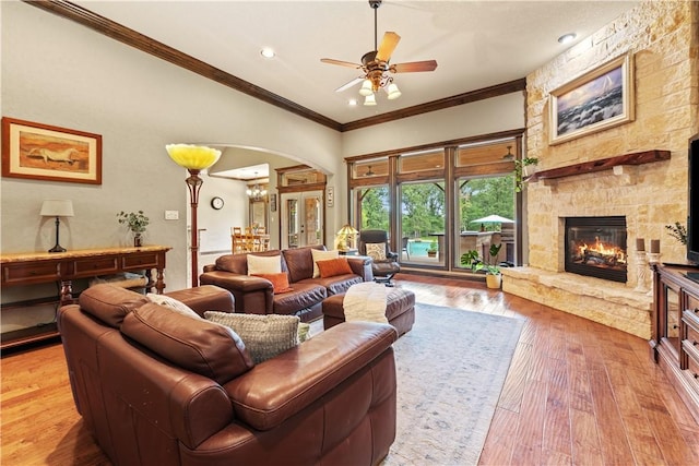 18265 Windmill Ct, College Station, TX 77845 - living area with arched walkways, ornamental molding, a fireplace, a ceiling fan, and light wood-style floors