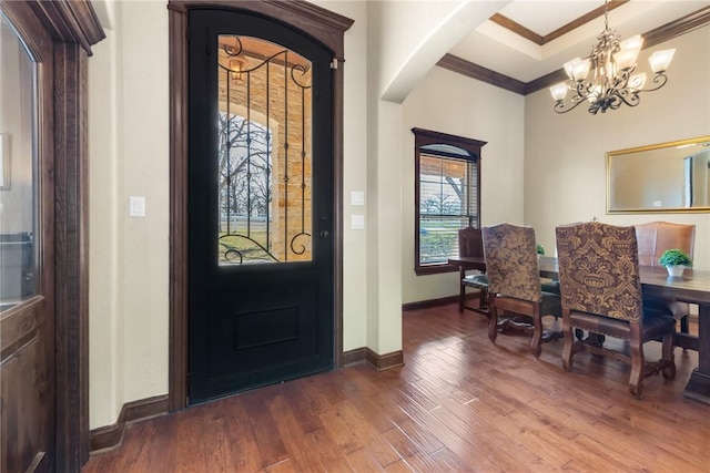 entrance foyer featuring a notable chandelier, baseboards, crown molding, dark wood-type flooring, and arched walkways