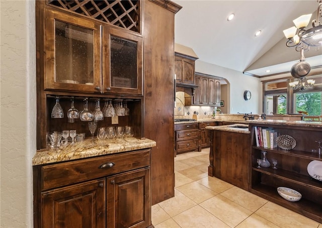 18265 Windmill Ct, College Station, TX 77845 - kitchen with vaulted ceiling, light tile patterned flooring, a chandelier, arched walkways, and light stone countertops