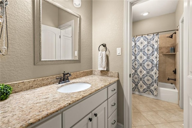 bathroom featuring a textured wall, tile patterned floors, shower / tub combo with curtain, and vanity