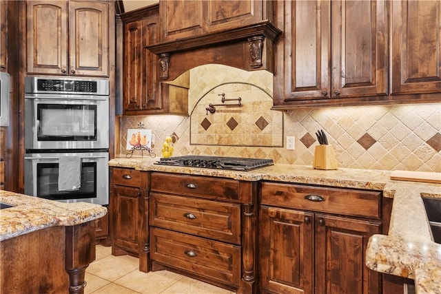 18265 Windmill Ct, College Station, TX 77845 - kitchen featuring appliances with stainless steel finishes, light stone counters, backsplash, and light tile patterned flooring