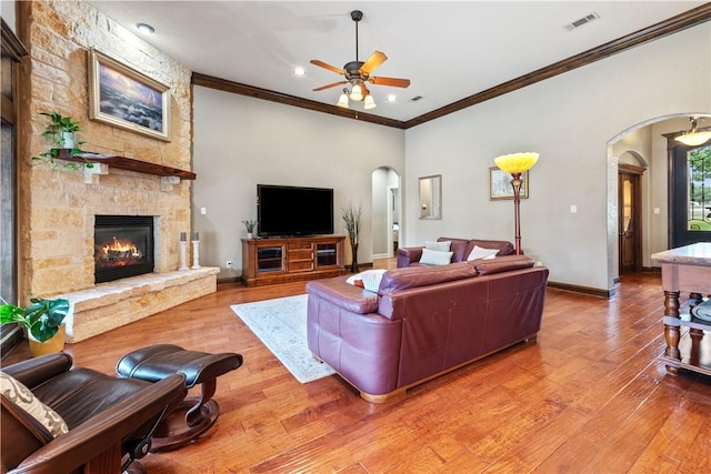 18265 Windmill Ct, College Station, TX 77845 - living room featuring arched walkways, ceiling fan, a fireplace, ornamental molding, and light wood-style flooring