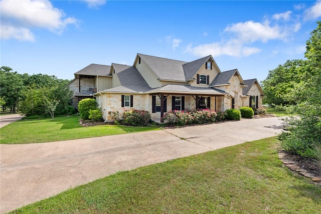 view of front of house featuring board and batten siding, driveway, stone siding, and a front lawn
