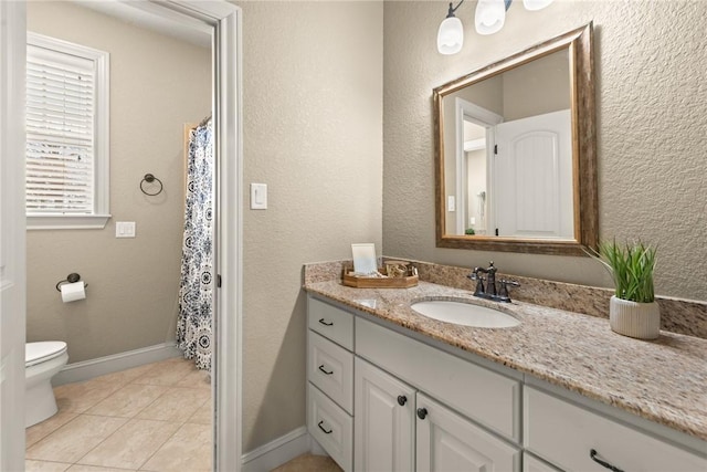 full bath featuring toilet, vanity, baseboards, and tile patterned flooring