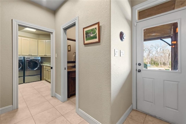 doorway to outside with a textured wall, baseboards, washer and clothes dryer, and light tile patterned floors