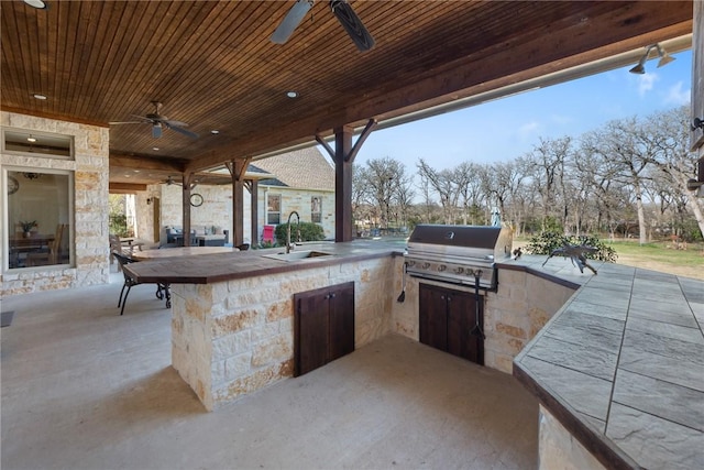 view of patio with exterior kitchen, a sink, outdoor wet bar, ceiling fan, and area for grilling