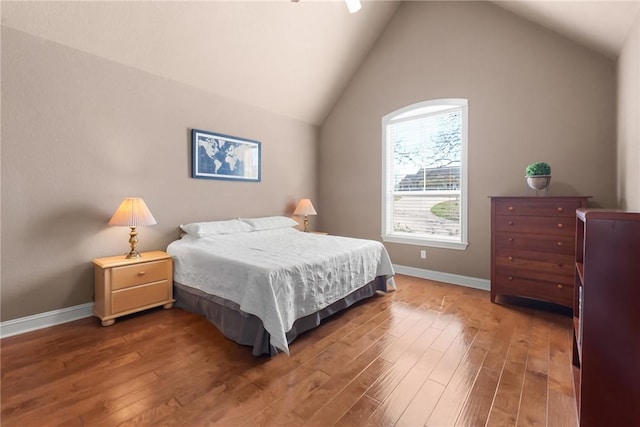 bedroom with baseboards, vaulted ceiling, and wood finished floors