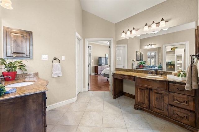ensuite bathroom with lofted ceiling, two vanities, and a sink