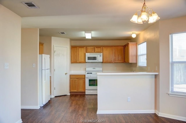 kitchen featuring white appliances, an inviting chandelier, decorative light fixtures, dark hardwood / wood-style flooring, and kitchen peninsula