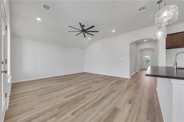 unfurnished living room with ceiling fan, lofted ceiling, sink, and light hardwood / wood-style flooring