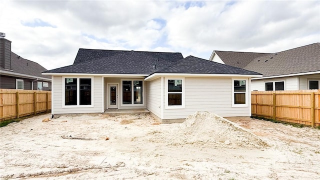 rear view of house featuring a shingled roof and a fenced backyard