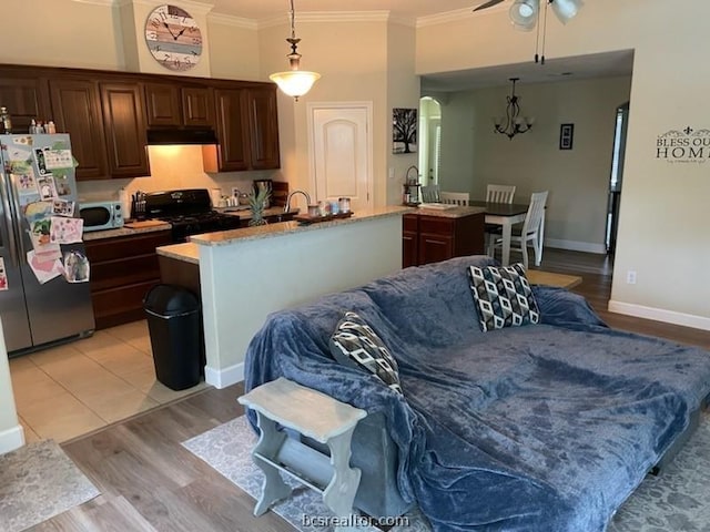 kitchen featuring stainless steel appliances, light hardwood / wood-style flooring, pendant lighting, a center island with sink, and ornamental molding