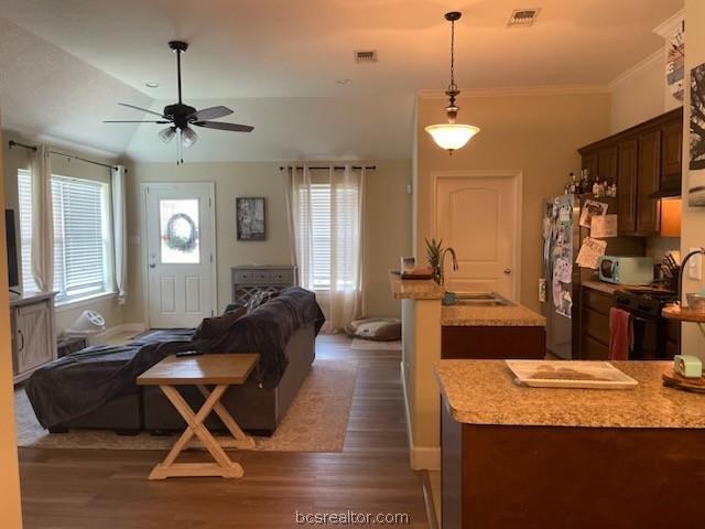 2402 Pleasant Rose Cir, Bryan, TX 77808 - kitchen with open floor plan, a ceiling fan, dark wood finished floors, plenty of natural light, and ornamental molding