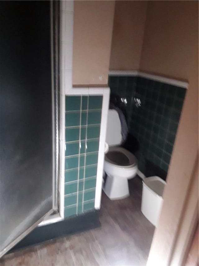 bathroom featuring tile walls and toilet