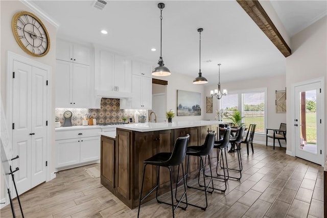 3310 Hunters Crossing Trl, Bryan, TX 77808 - kitchen featuring light countertops, tasteful backsplash, white cabinetry, an island with sink, and a breakfast bar
