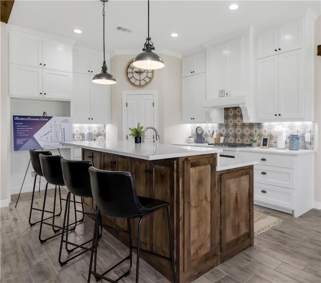 3310 Hunters Crossing Trl, Bryan, TX 77808 - kitchen featuring light countertops, an island with sink, backsplash, white cabinetry, and recessed lighting