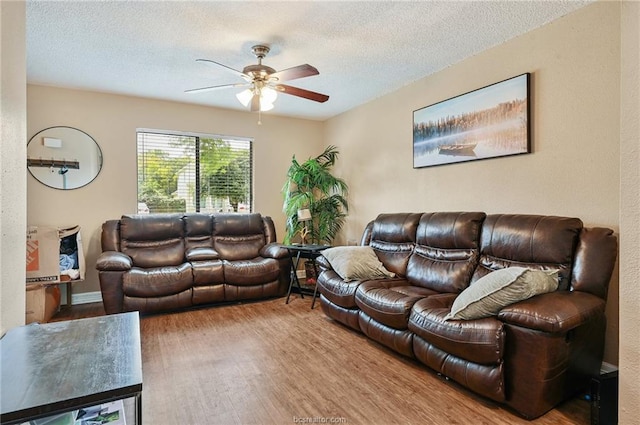 living area featuring wood finished floors, a textured ceiling, and ceiling fan