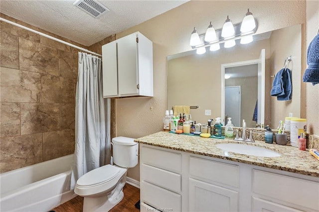 full bathroom with wood finished floors, visible vents, a textured ceiling, toilet, and a textured wall