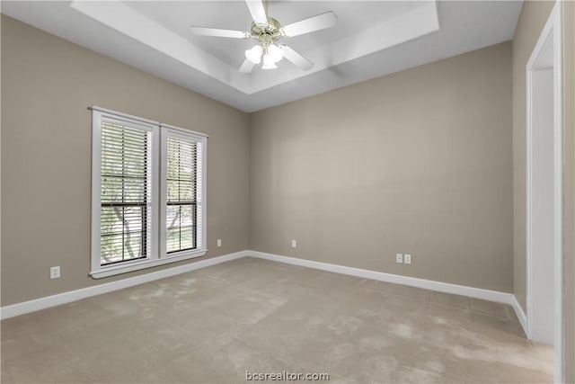 carpeted empty room featuring ceiling fan and a tray ceiling