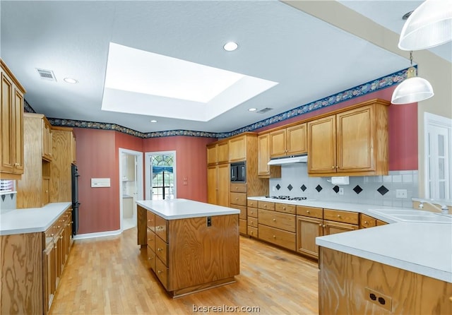 kitchen featuring a skylight, tasteful backsplash, sink, pendant lighting, and a center island