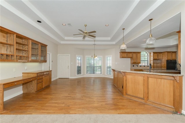 9300 Lakeside Ct, College Station, TX 77845 - kitchen featuring a ceiling fan, brown cabinets, a raised ceiling, light wood-type flooring, and pendant lighting