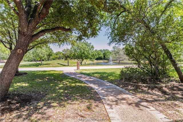 view of property's community with a lawn and a water view