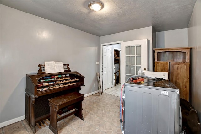 bedroom with washer / dryer, a textured ceiling, and baseboards