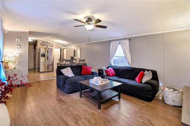 living area with lofted ceiling, crown molding, a ceiling fan, and light wood finished floors