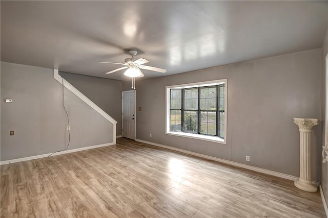 unfurnished living room featuring baseboards, light wood-type flooring, and ceiling fan