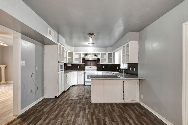 kitchen featuring open shelves, a sink, dark wood-style floors, white appliances, and a peninsula