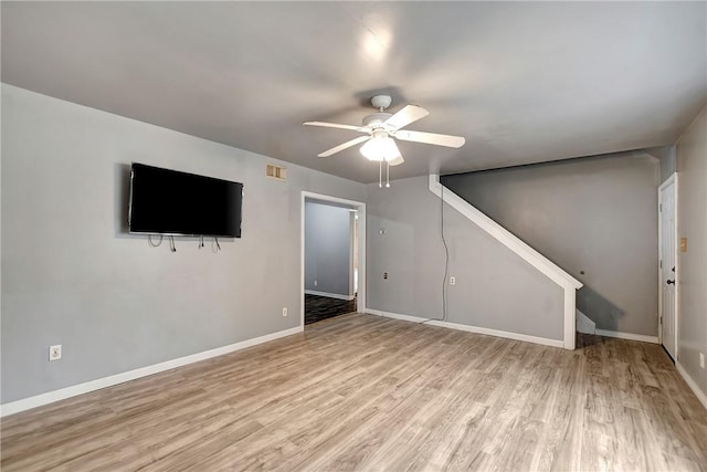 unfurnished living room with visible vents, a ceiling fan, light wood-style floors, baseboards, and stairs